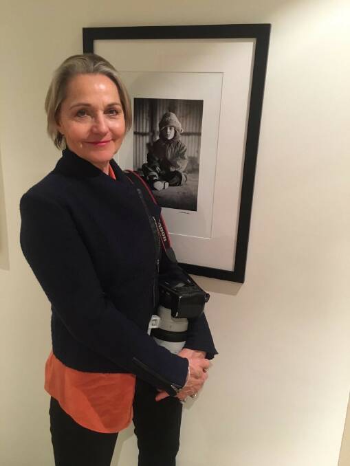 Photographer Tina Milson standing in front of one of her portraits. Photo: Supplied.