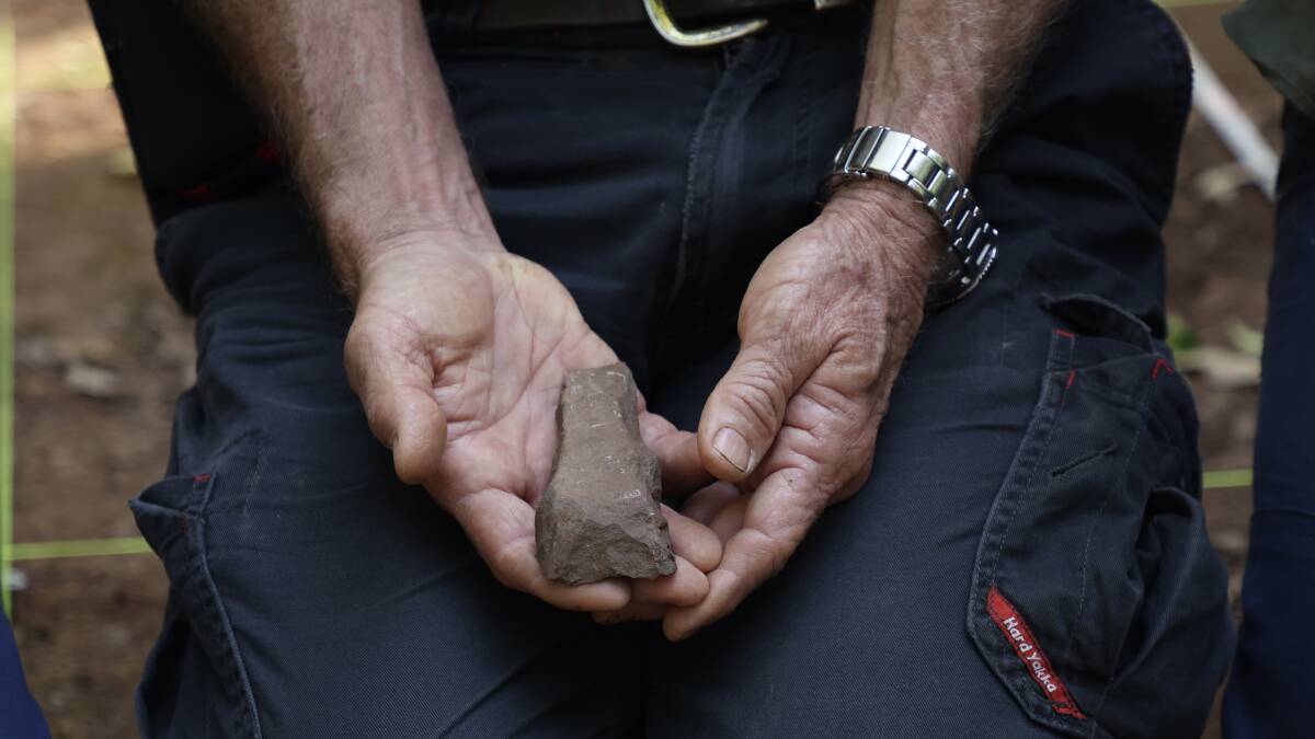 Snowy Tavener holds one of the adzes (ancient cutting tools). Picture by Tom Bannigan/Australian Museum