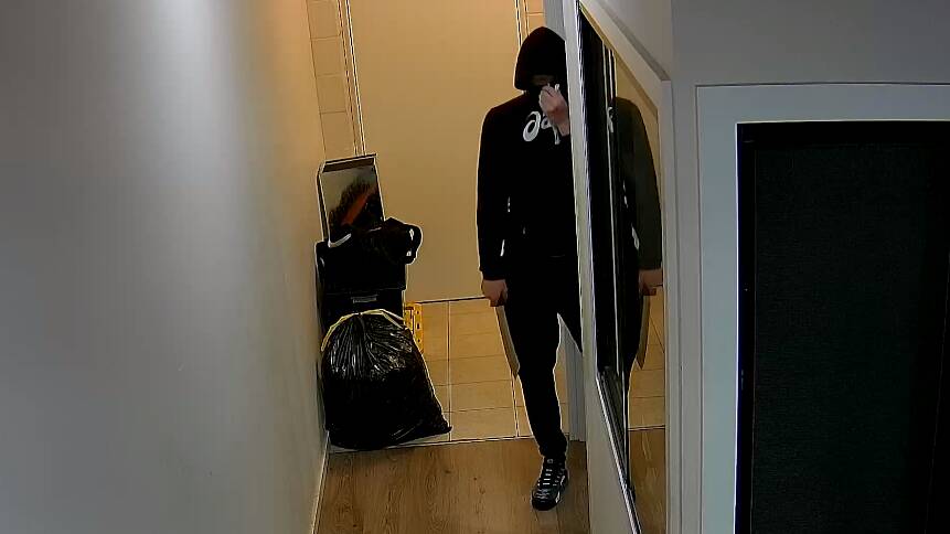 A still footage of an alleged robber holding a machete in the store's backroom. Picture via Queensland Police