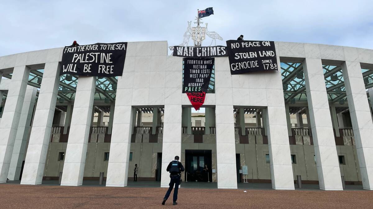 An AFP officer stands in front of Parliament House where protestors scaled the roof to unfurl banners on Thursday. Picture by Brittney Levinson