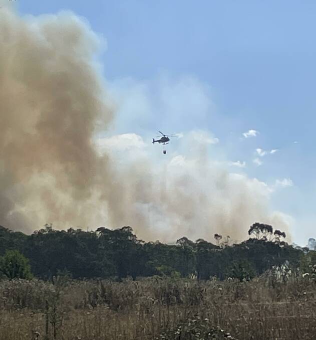 A helicopter is one of two aircraft water bombing the fire off Jerrara Road, near Marulan. Photo by Cameron Shelley.