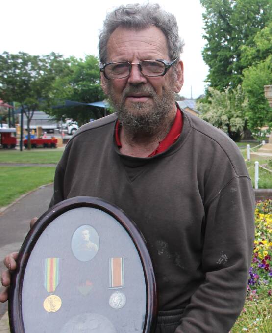 MEDALS: John Walker holding a photo and the medals of his grandfather's friend, Cameron James Brooks, who died at the Somme. 