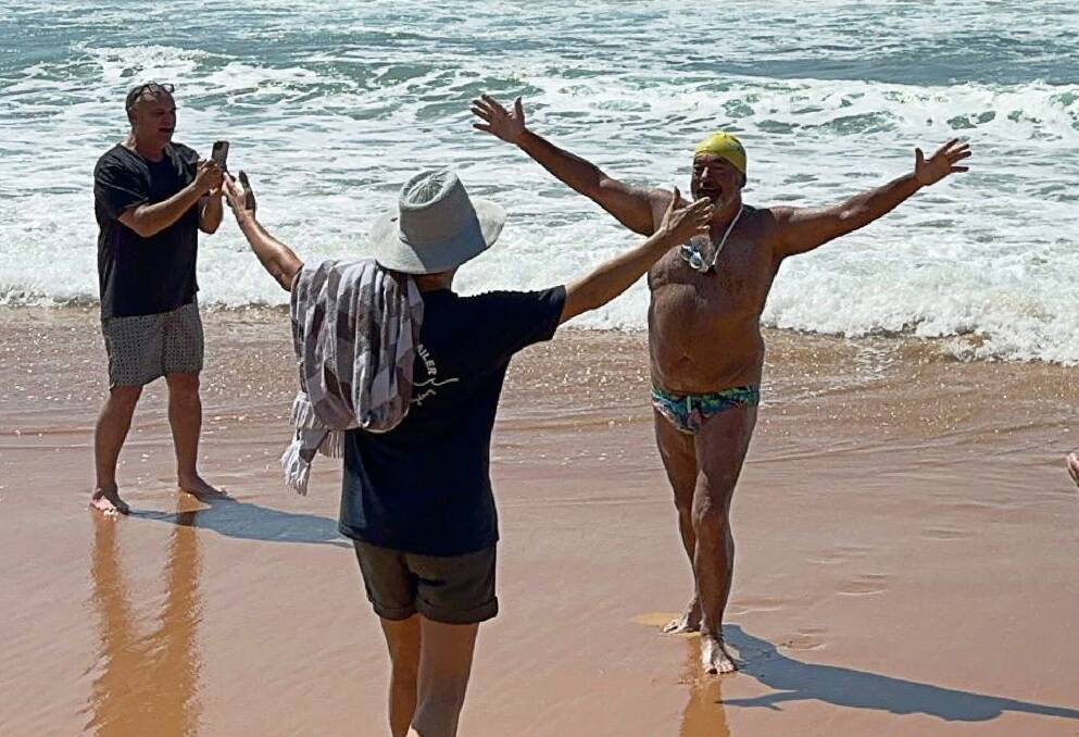 Dean Summers celebrates upon completion of his epic Newcastle to Sydney swim at Palm Beach. Photo supplied 