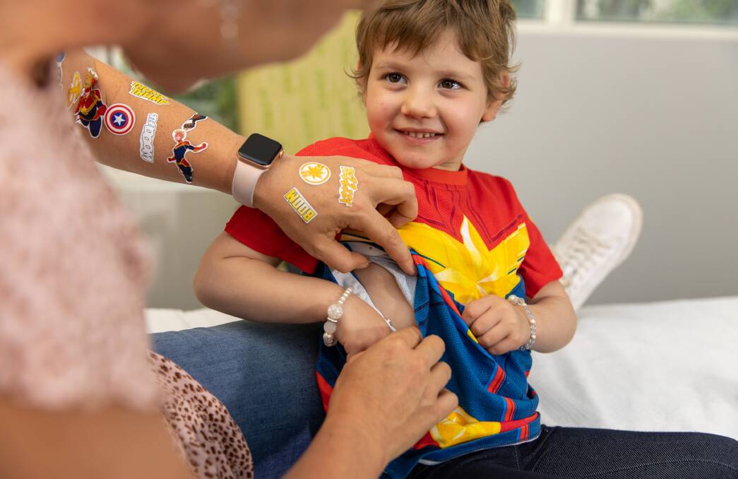 Isla Crotty is checked over, while wearing a Captain Marvel themed Supertee. Almost 100 of the cleverly disguised medical garments have been donated to Goulburn Hospital. Picture supplied. 