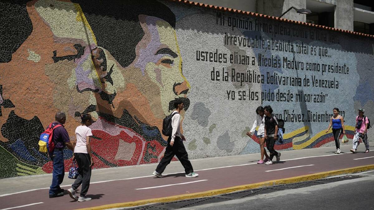 Venezuelans pass a mural of late president Hugo Chavez and Nicolas Maduro in Caracas. (AP PHOTO)