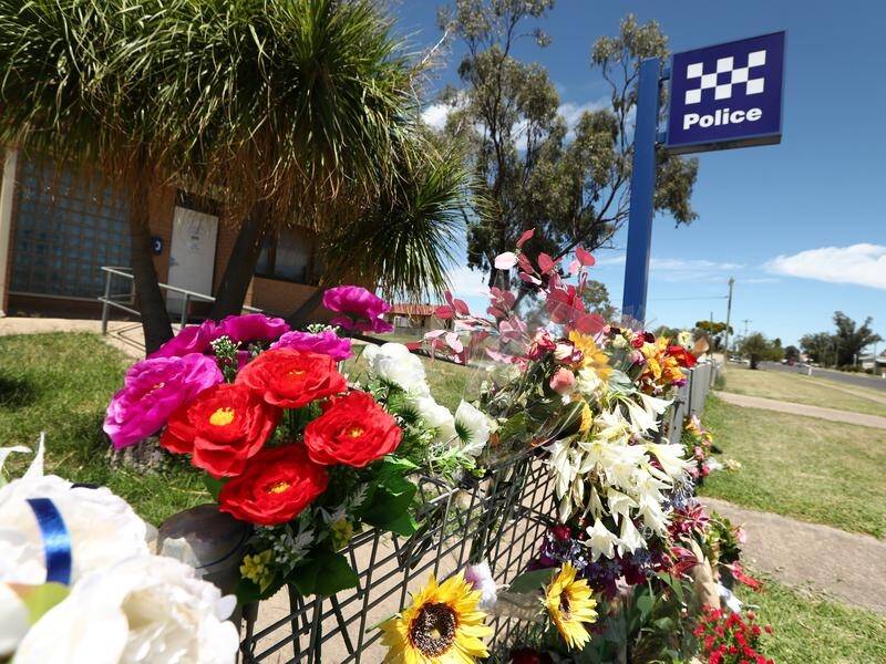 Tributes to the Wieambilla shooting victims are seen outside the Tara Police Station in Queensland. (JASON O'BRIEN/AAP PHOTOS)