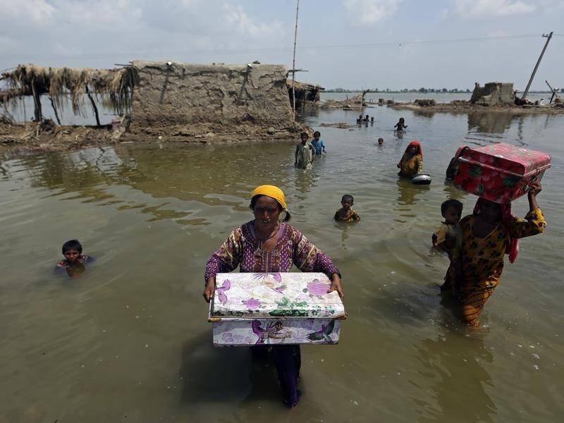 Women salvage belongings from their flooded homes after monsoon rains in Sindh Province, Pakistan. (AP PHOTO)