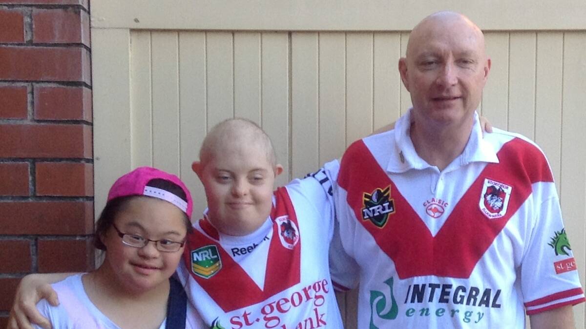 GO THE RED V: Connor is a big St George Illawarra Dragons fan. Connor (middle)
with his mate Maddie (left) and his dad, Kerry (right).