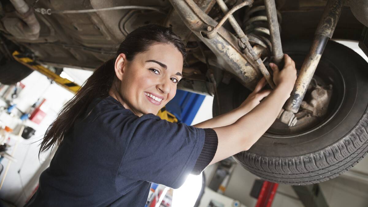 A young female mechanic inspects a car in an auto repair shop.
