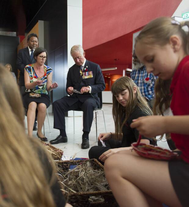 Charles tries his hand at basket making with school students at the National Museum of Australia in 2015. Picture by Jay Cronan